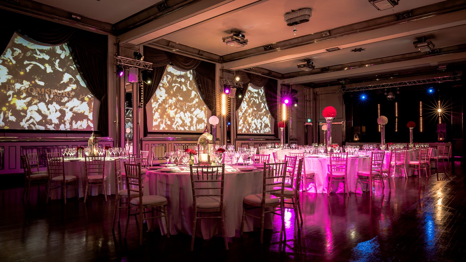 The art deco Bloomsbury Ballroom dressed for a wedding with dramatic pink lighting, London